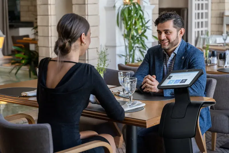 temi mit Display neben Personen an einem Tisch.